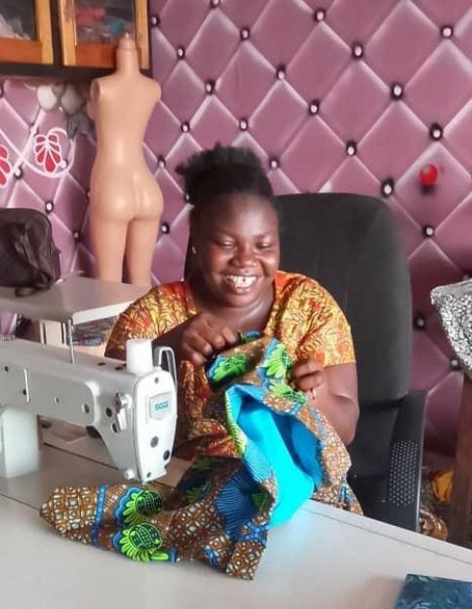 Mercy Amankwah happily sewing a beautiful dress for her clients.